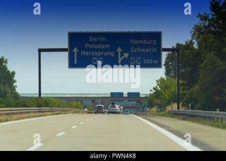 German motorway sign with inscription in German direction arrow to the cities - Berlin, Potsdam, Herzsprung, Hamburg and Schwerin Stock Photo
