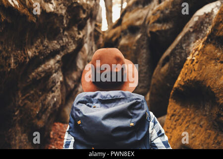 Travel young woman wearing brown hat, plaid shirt, jeans and brown boots with backpack looking on wonderful canyon with moss on rocks after hiking, travelling concept Stock Photo