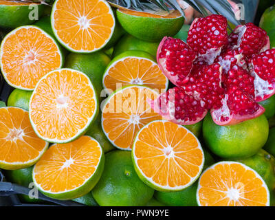 close up of sliced pomeranate lays on vivid cutted oranges, juicy exotic fruits Stock Photo