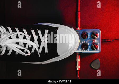 Guitar pedals and footswitch inside recording room. Close up of guitar pedals and musician's foot tapping on it for different sounds. Macro view. Stock Photo