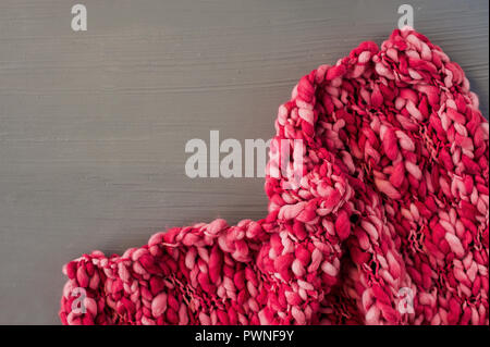 Pink knitting pattern on gray background. Space for text. Top view Stock Photo