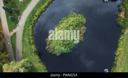 Aerial Drone Flight: View of the lake with oil stains from the road. Stock Photo