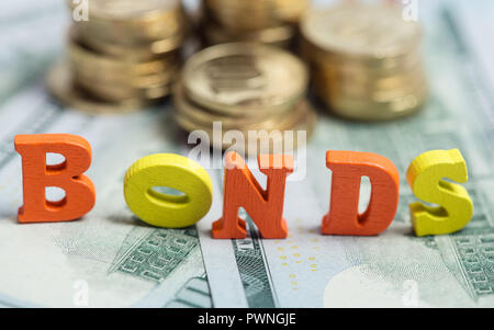Bonds investment at wooden letters on US Dollar bills and golden coins Stock Photo