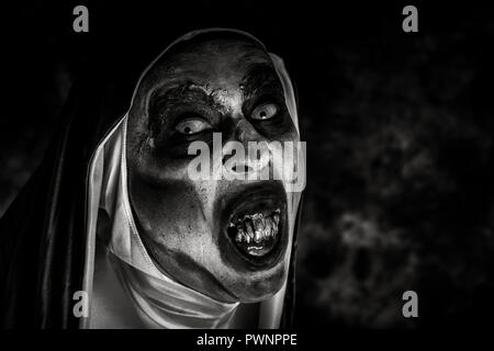 closeup of a scary evil nun, with frightening teeth, wearing a typical black and white habit, in black and white Stock Photo