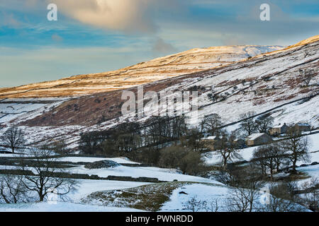 High view looking up remote scenic valley of Langstrothdale, Yockenthwaite Farm nestling under snow covered hills & blue sky - North Yorkshire, GB, UK Stock Photo