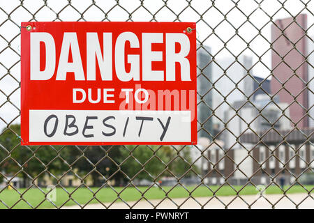 Sign danger due to obesity attached on the fence in the front of the town Stock Photo