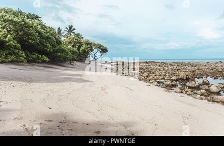 Pristine white sand beach on the edge of the forest with a rocky shore near Manzanillo, Costa Rica Stock Photo