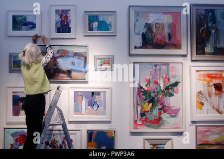London, UK. 17th Oct, 2018. an exhibitor hangs artworks on the Rosvik Gallery exhibition at the Affordable Art Fair in Battersea Park, London, Wednesday October 17, 2018. The art fair promises all artwork on sale is beneath £6,000 and runs until October 21. Photograph : Credit: Luke MacGregor/Alamy Live News Stock Photo
