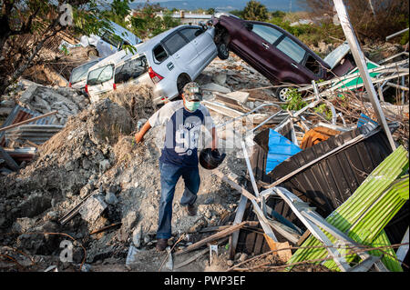 Sigi, Indonesia. 17th Oct, 2018. A man is seen walking around the damaged building after the earthquake. A deadly earthquake measuring 7.5 magnitude and the tsunami wave caused by it has destroyed the city of Palu and much of the area in Central Sulawesi. According to the officials, death toll from devastating quake and tsunami rises to 2088, around 5000 people in hospitals are seriously injured and some 62,000 people have been displaced. Credit: SOPA Images Limited/Alamy Live News Stock Photo