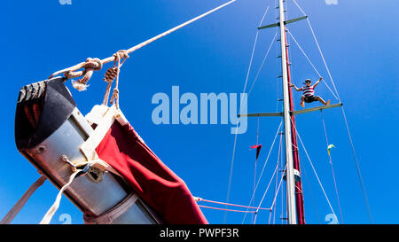 A kid 7 years old, climbing in a mast of a sailing boat, Clifton, Union island, Lesser Antilles, West Indies Stock Photo