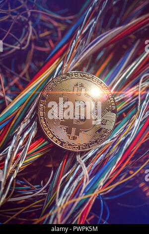 Bitcoin crypto currency coin on the top of colorful bundle of cables/wires Stock Photo