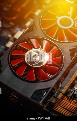 Cryptocurrency mining concept closeup with golden ethereum on top of a computer performant video card red fans Stock Photo