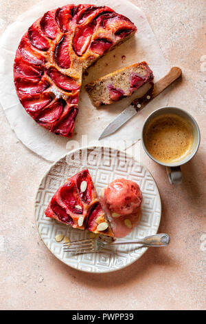 Upside-down plum cake on a plate served with a dollop of ice cream. Stock Photo