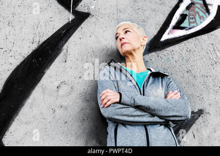 Senior Woman Relax After Running, Leaning On Wall. Short-Gray Hair, Sports Clothes ,