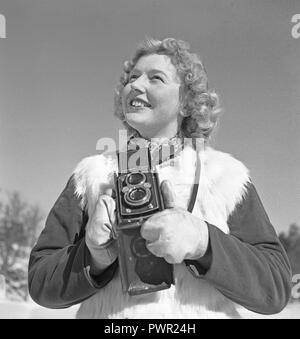 Winter in the 1940s. A young woman is photographing on a winter day. The camera is a Rolleiflex by the german company Rolle for 60 mm film.  Sweden 1944. Photo Kristoffersson Ref F31-6 Stock Photo