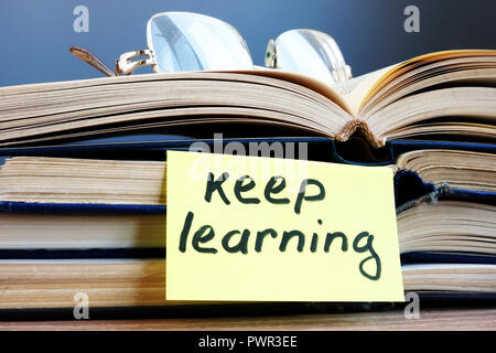 Keep learning. Open book and glasses on the table. Stock Photo