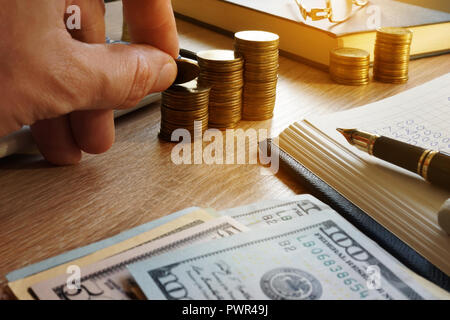 Man holding coin. Desk with calculator, money and financial calculations. Stock Photo