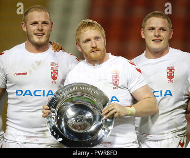 England's James Graham lifts the Paul Barriere shield after his teams win against France with Tom Burgess (left) and George Burgess (right), during the International match at Leigh Sports Village. Stock Photo