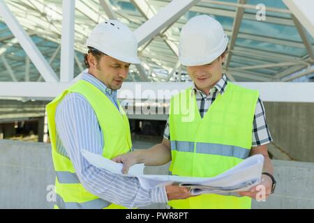 Male construction worker and engineer at the construction site. Building, development, teamwork and people concept. Stock Photo