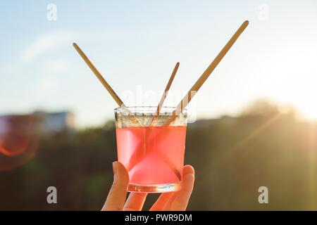Brushes of the artist in glass with water on wooden white window ledge. Background sky, silhouette of the city, sunset. Stock Photo