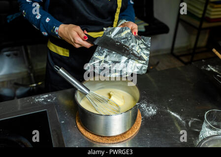 adding butter from a pack to a cream made by hand Stock Photo