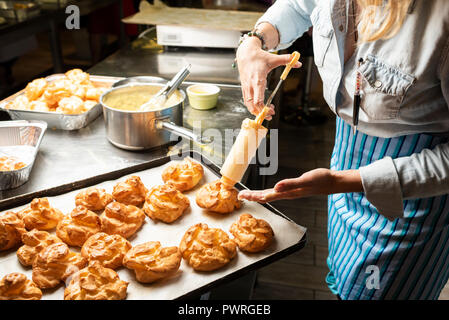 filling the eclairs with a confectionery syringe with female hands Stock Photo