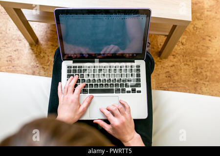 Concentrated young man with glasses working on a laptop in a home office. Corrects text, close-up Stock Photo