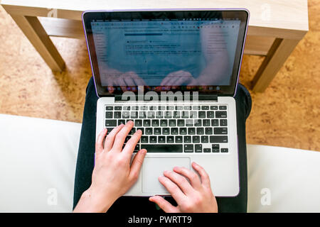 Concentrated young man with glasses working on a laptop in a home office. Corrects text, close-up Stock Photo