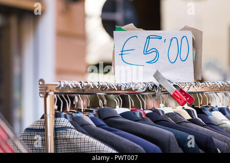 Coat rack with a large variation of men suits second hand for sell at cheap price at a street market in Ancona Italy. Stock Photo