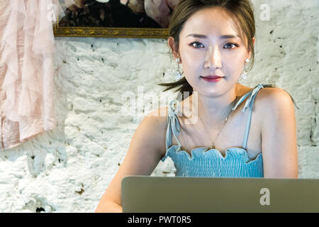 Amsterdam, Netherlands - July 23th, 2018: Portrait of a Japanesse woman working using her laptop at her clothes store in Amsterdam. Stock Photo