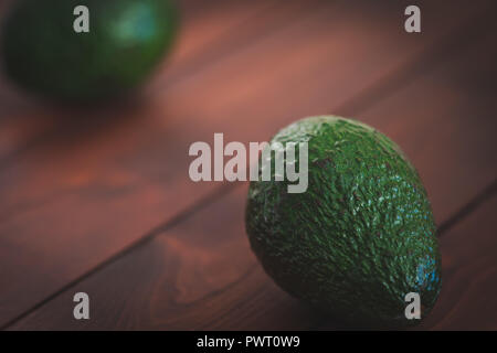 Two avocados on a brown cutting board. Stock Photo