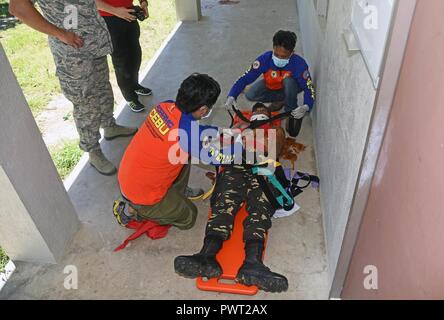 Members of the provincial Disaster Risk Reduction Management Office strap a volunteer with simulated chest injuries to a long spine board during a mass casualty response exercise at Bogo City Hall, Northern Cebu Province, Philippines, June 25, 2017. As part of Pacific Angel 2017, local first responders worked together with U.S. and Philippine forces to share and teach best practices in public health, mass casualty response and other relevant topics. Stock Photo