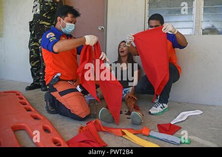 Members of the provincial Disaster Risk Reduction Management Office treat a volunteer with a simulated leg injury during a mass casualty response exercise during Pacific Angel 2017 at Bogo City Hall, Northern Cebu Province, Philippines, June 25, 2017. As part of PACANGEL 2017, local first responders worked together with U.S. and Philippine forces to share and teach best practices in public health, mass casualty response and other related topics. Stock Photo