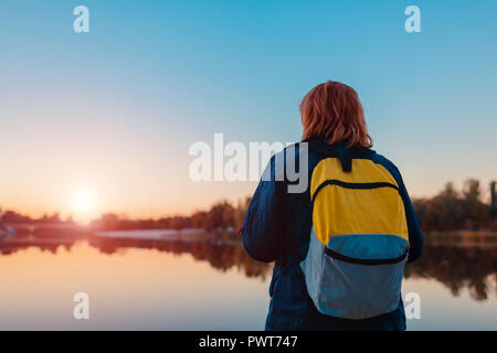 Tourist with backpack walking in autumn forest. Middle-aged woman travelling alone. Active lifestyle Stock Photo