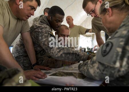 U.S. Army Reserve Soldiers from the 384th Military Police Battalion, headquartered in Fort Wayne, Indiana, hover over a map to plot an upcoming convoy during a Warrior Exercise (WAREX) held at Fort Hunter Liggett, California, June 19. The MP battalion's Soldiers and leadership originally arrived thinking they would train on detainee and enemy prisoner of war operations, but instead they were tasked to train on housing displaced civilians during a two-week WAREX, with temperatures reaching 100-plus degrees daily. Stock Photo