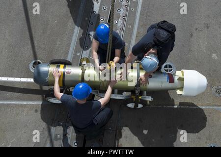 Sailors secure a Mark 46 Mod 5A torpedo on the flight deck aboard USS ...
