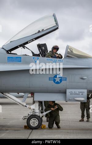 U.S. Marine Corps Capt. Jared G. Cox, top, a pilot assigned to Marine Fighter Attacks Squadron 251, prepares to exit an F/A-18C Hornet during Red Flag-Alaska 17-2 on Joint Base Elmendorf-Richardson, Alaska, June 21, 2017. Red Flag-Alaska provides an optimal training environment in the Indo-Asian Pacific region and focuses on improving ground, space, and cyberspace combat readiness and interoperability for U.S. and international forces. Stock Photo