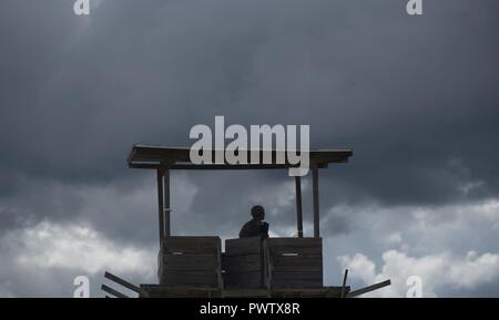 A U.S. Army Reserve military police with the 325th MP Company, out of Fresno, California, pulls guard duty under a dark, angry sky during Guardian Justice at Fort McCoy, Wisconsin, June 24. Guardian Justice is a functional exercise, broken down into two-week cycles, centered on squad and team-level training with a focus on internment, resettlement, detainee operations and combat support. During each two-week cycle, Soldiers train on internment operations, weapons qualification, biometrics, reflexive fire, Military Operations on Urbanized Terrain (MOUT), non-lethal Tasers, MP battle drills and  Stock Photo