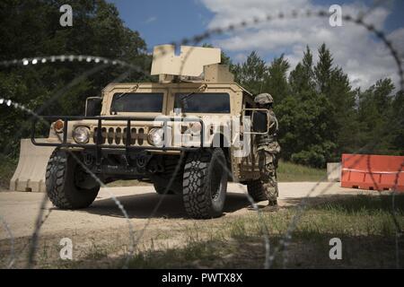 A U.S. Army Reserve military police with the 325th Military Police Company, out of Fresno, California, checks identification cards at an entry control point during Guardian Justice at Fort McCoy, Wisconsin, June 24. Guardian Justice is a functional exercise, broken down into two-week cycles, centered on squad and team-level training with a focus on internment, resettlement, detainee operations and combat support. During each two-week cycle, Soldiers train on internment operations, weapons qualification, biometrics, reflexive fire, Military Operations on Urbanized Terrain (MOUT), non-lethal Tas Stock Photo