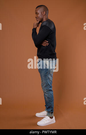 Studio shot of young African man against brown background Stock Photo