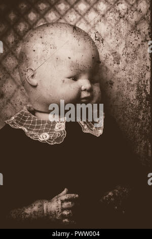 A portrait of a creepy old doll, made to look like a posed baby. The image is done to look like an old photograph. Doll is wearing a vintage dress. Stock Photo
