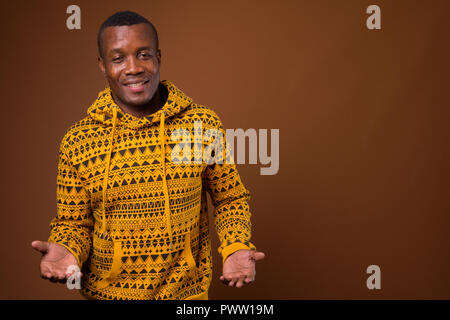 Studio shot of young African man against brown background Stock Photo