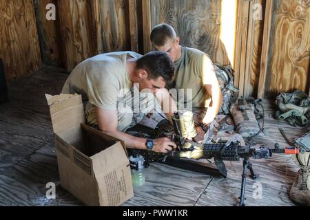 FORT IRWIN, Calif. – Two infantrymen from Killer Troop, 3rd Squadron, 3rd Cavalry Regiment prepare their M240B Machine Gun for combat, prior to moving toward defensive positions in wait for the 1st Stryker Brigade Combat Team, 4th Infantry Division’s assault on the village of Huvez, in the National Training Center, June 26, 2017. This phase of NTC Rotation 17-07.5 challenged the Raider Brigade’s ability to conduct zone reconnaissance and prepare the area of operations for follow on forces. Stock Photo