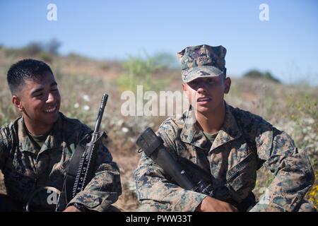 U.S. Marine Lance Cpls. Luis Orozohernandez and Lance Cpl. Luis Mejia, motor transportation operators for Combat Logistics Battalion 5, Headquarters Regiment, 1st Marine Logistics Group take a break during a seven mile conditioning hike on Camp Pendleton, Calif., June 27, 2017. The Marines have multiple conditioning hikes to prepare for Mountain Exercise 4-17 which will be conducted at the Marine Corps Mountain Warfare Training Center in Bridgeport, Calif. Stock Photo