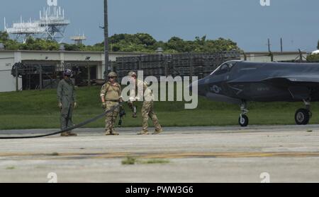 U.S. Marines and Airmen finish a hot pit refuel on the F-35B Lightning II aircraft at Kadena Air Force Base, Okinawa, Japan, June 27, 2017. The Marines are with Marine Fighter Attack Squadron 121, Marine Aircraft Group 12, 1st Marine Aircraft Wing, and the Airmen are with 353 Special Operations Group, 18th Wing. The two-day exercise enabled the U.S. Air Force and Marine Corps to improve interoperability and develop tactics, techniques and procedures involving the new aircraft for future joint FARP operations throughout the Indo-Asia Pacific Theater. Stock Photo