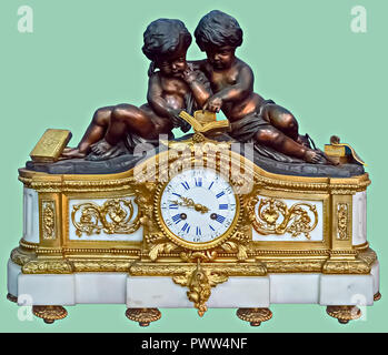 Antique mantel clock of a bronze statuettes holding and reading book, on isolated green background with clipping path. Stock Photo