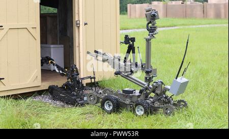 A TALON Robot, controlled by Soldiers assigned to 705th EOD Company, 63rd EOD Battalion, 52nd EOD Group, 20th CBRNE Command, and a Mini ANDROS II Robot,  controlled by personnel assigned to Rapides Parish Sheriff’s Office, La., inspect a cabin with explosives during Raven’s Challenge 2017 at Camp Shelby, Miss., June 29, 2017. Raven’s Challenge is an annual training event that provides Explosive Ordnance Disposal personnel and Public Safety Bomb Squads of both military and government agencies interoperability in a realistic domestic tactical environment. Stock Photo