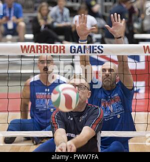 United Kingdom's Army Sgt. John Dixon bumps the ball as U.S. Air Force veteran Tech. Sgt. Joshua Smith waits for a chance to block during preliminary sitting volleyball competition at the 2017 Department of Defense ) Warrior Games in Chicago, Ill., June 30, 2017. Behind them is U.S. Air Force Tech. Sgt. Jason Caswell. The DoD Warrior Games are an annual event allowing wounded, ill and injured service members and veterans to compete in Paralympic-style sports including archery, cycling, field, shooting, sitting volleyball, swimming, track and wheelchair basketball. Stock Photo