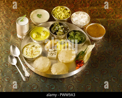 A FULL TRADITIONAL GUJARATI MEAL/ GUJARATI THALI: SHRIKHAND, RASMALAI,UNDHIYUN,TURIYA-PATRA VEGETABLE,KHAMAN DHOKLA, WHITE DHOKLA,GHOOGHARA,PURI, PAPA Stock Photo