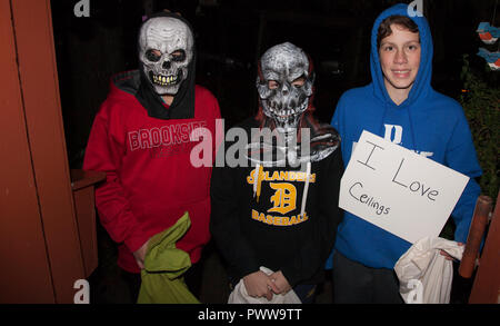 Three young teenage boys in skull masks and a ceiling lover costumes out for an evening of Halloween tricks or treats.  St Paul Minnesota MN USA Stock Photo